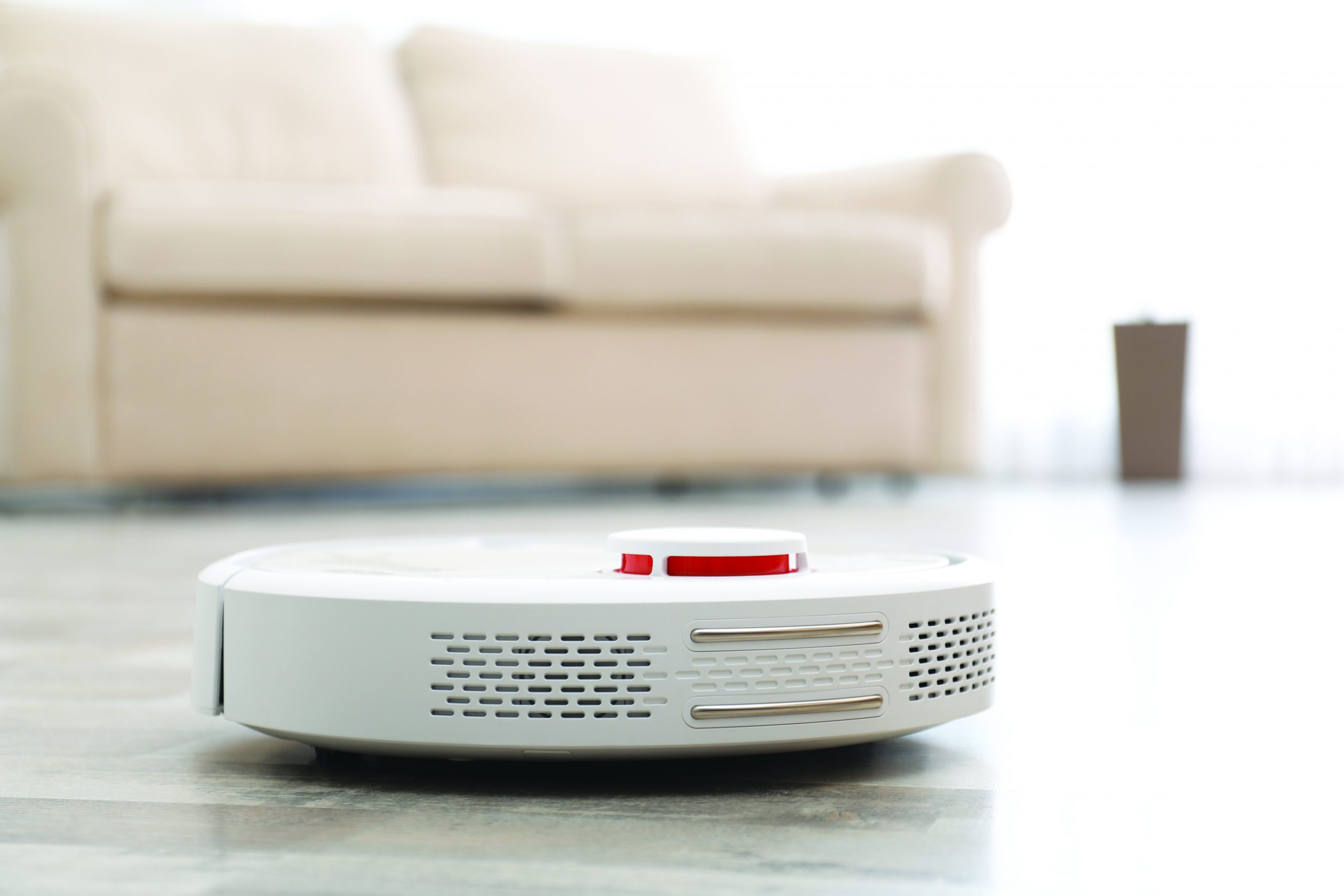 Modern robotic vacuum cleaner on floor in living room. Space for