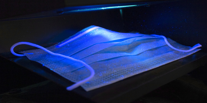 Medical mask under ultraviolet light to reveal germs
