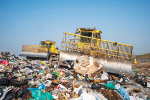 Workers with trucks and bulldozers at a municipal waste landfill